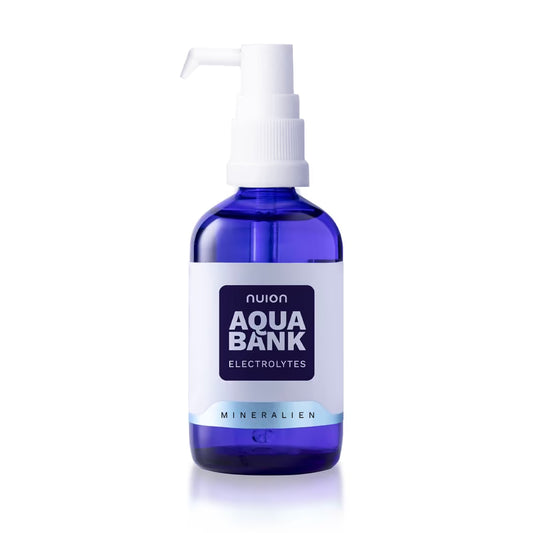 Eine blaue Glasflasche mit Pumpe enthält das Produkt Aqua Bank von Puromedica, das Elektrolyte enthält.