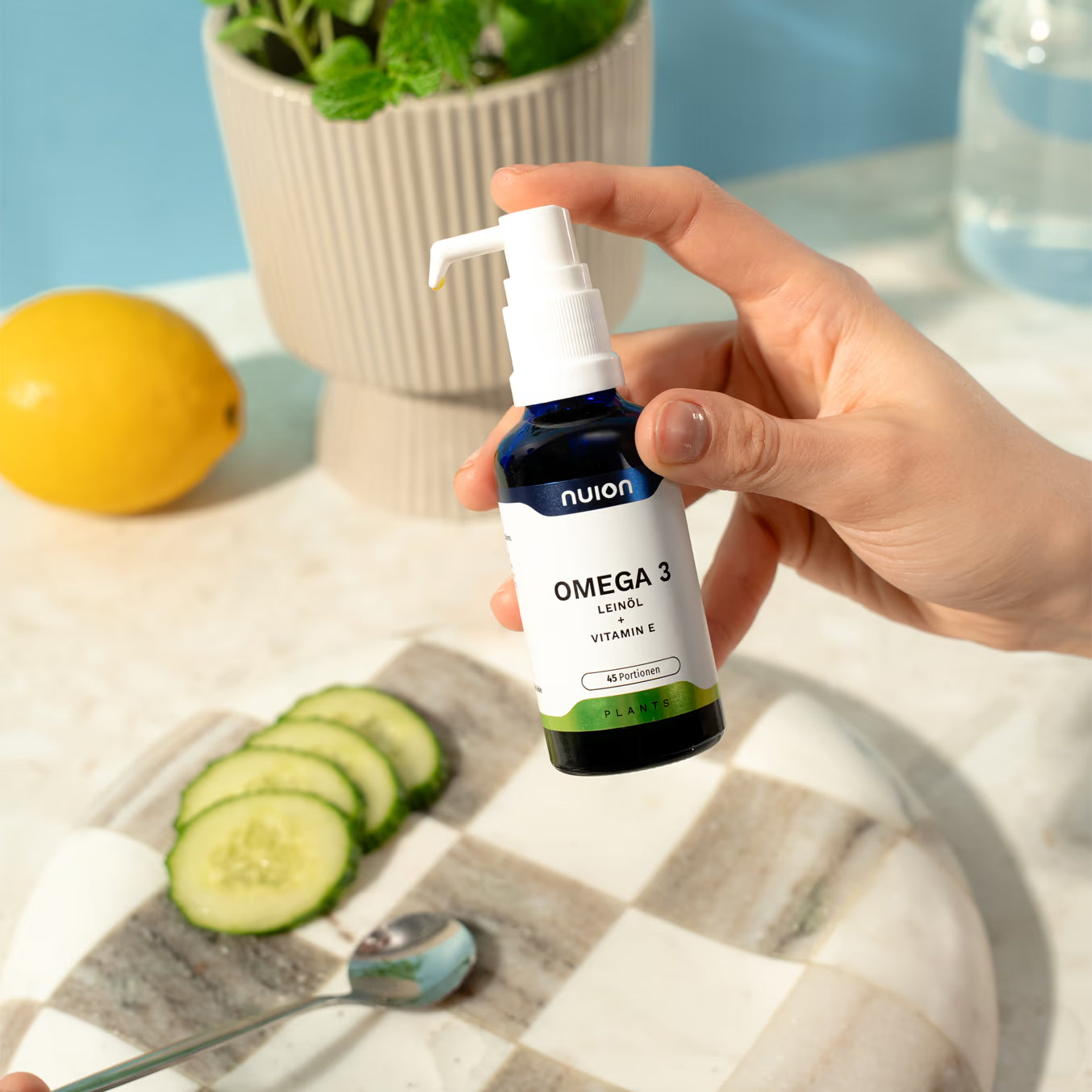 Eine Hand hält eine Flasche mit dem Produkt Omega 3 von Puromedica, das in einem blauen Glasbehälter mit einem weißen Pumpkopf verpackt ist.