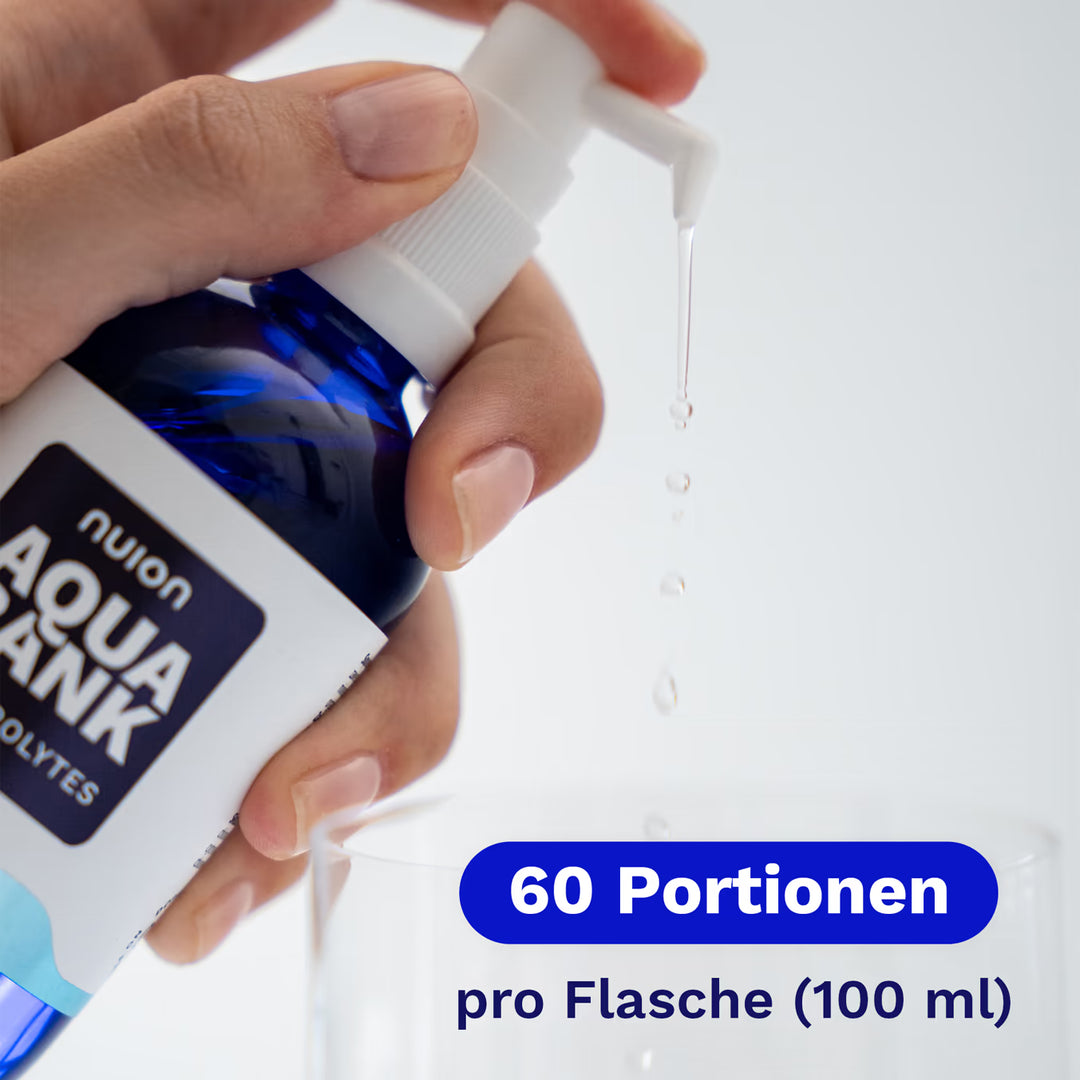 Eine Person hält eine Flasche Aqua Bank nuion - Elektrolyte von Puromedica in der Hand und drückt den Pumpmechanismus, während einige Tropfen in ein Glas fallen.