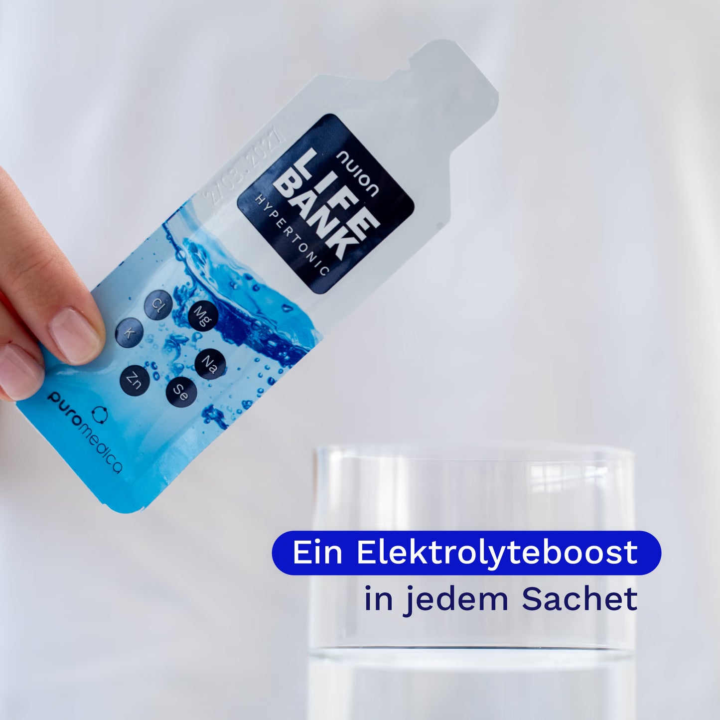 Eine Hand hält ein Sachet von Life Bank nuion - Hypertonisch über ein Glas Wasser. Auf dem Sachet sind die wichtigsten Nährstoffe und der Markenname Puromedica deutlich sichtbar, während das Wasser im Glas für einen Elektrolyteboost.