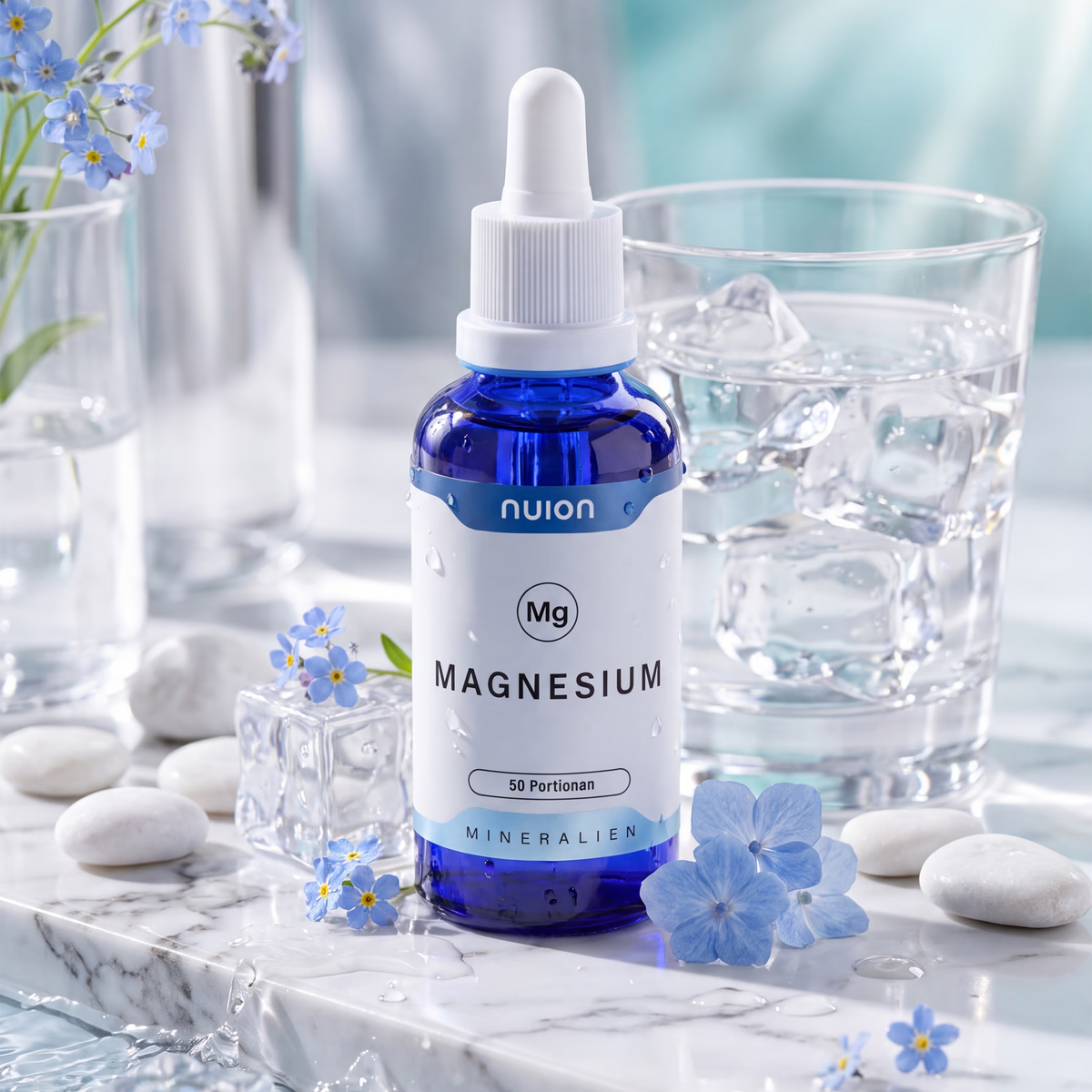 Ein blauer Fläschchen mit der Aufschrift nuion Magnesium steht auf einem marmorierten Tisch, umgeben von Eiswürfeln und einem Glas Wasser.
