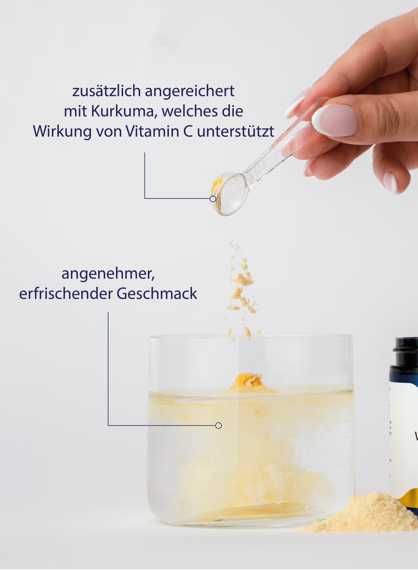 Eine Hand hält einen Messlöffel mit einem gelben Pulver über ein Glas, in dem sich eine klare Flüssigkeit befindet.